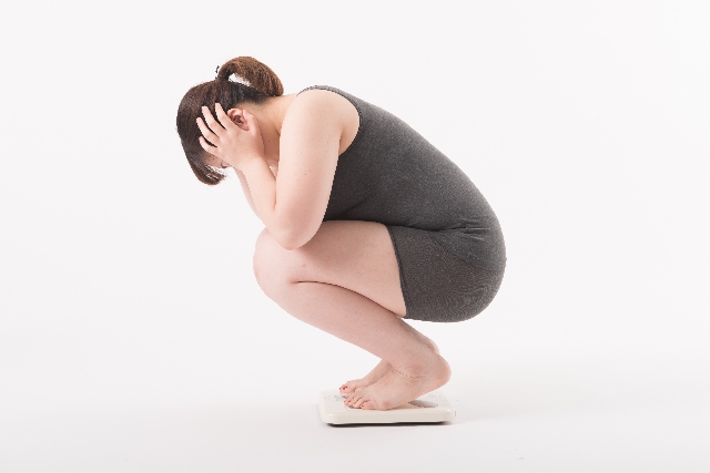 体重計にのり困っている女性